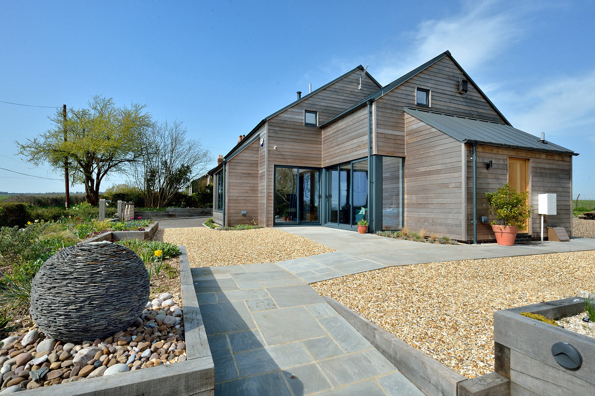 Modern rural house with timber cladding and metal roof view from rear garden