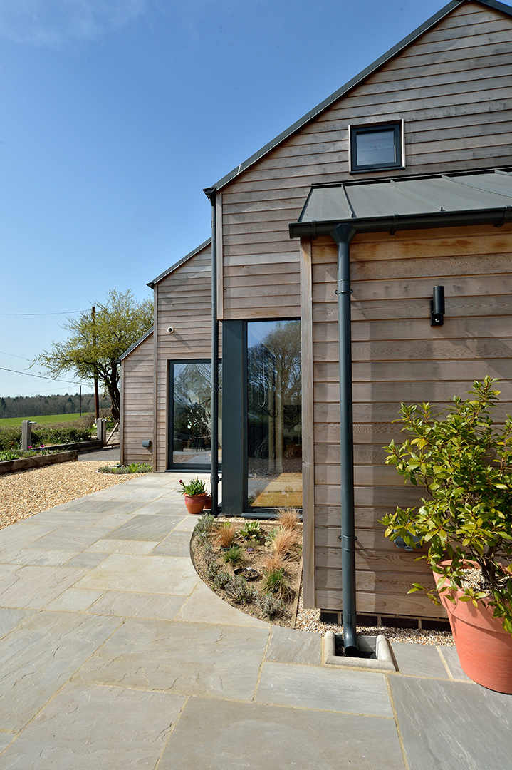 Detailed photo of modern rural house with timber cladding and metal roof view from patio