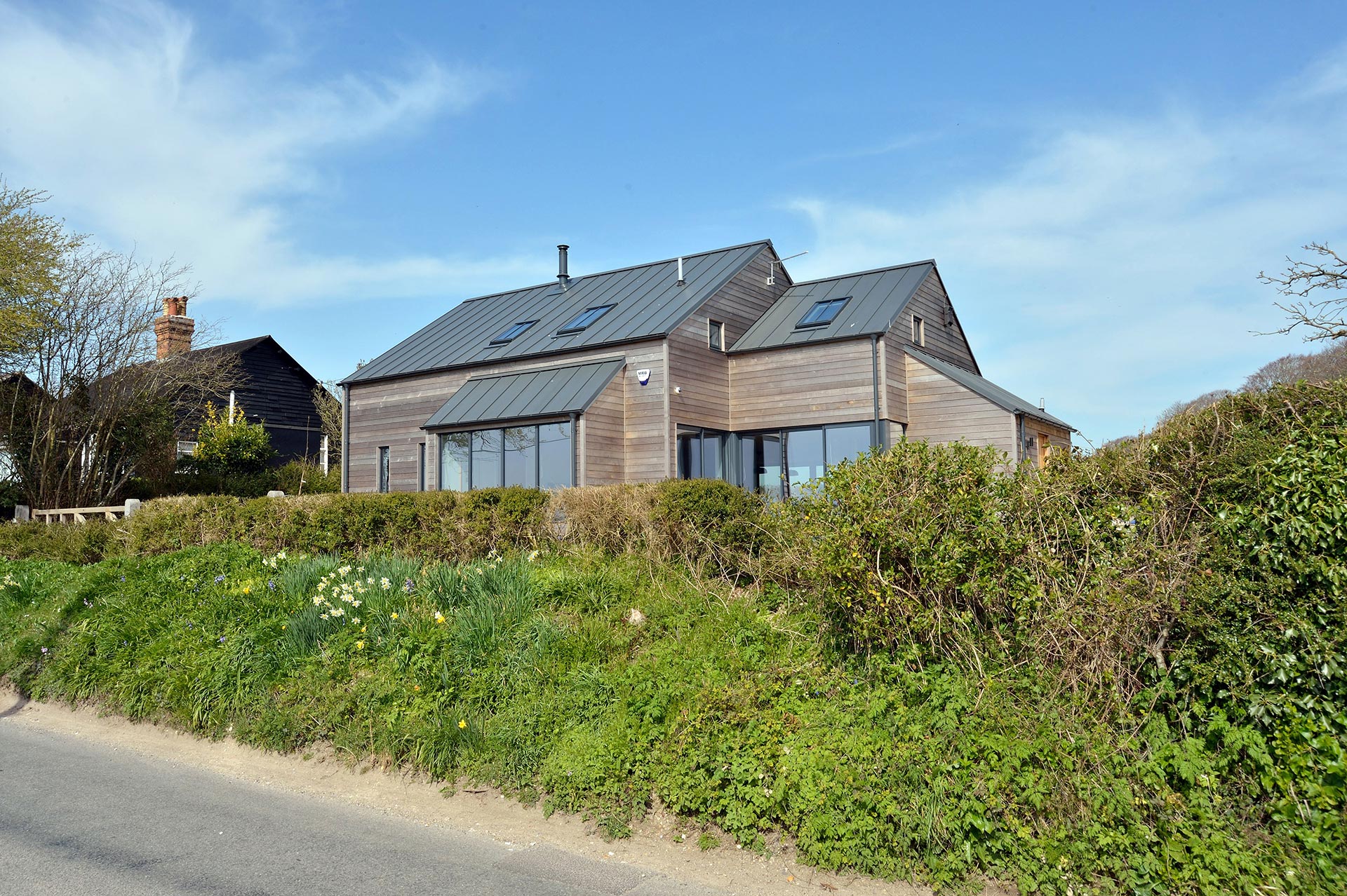 Modern rural house with timber cladding and metal roof view from road
