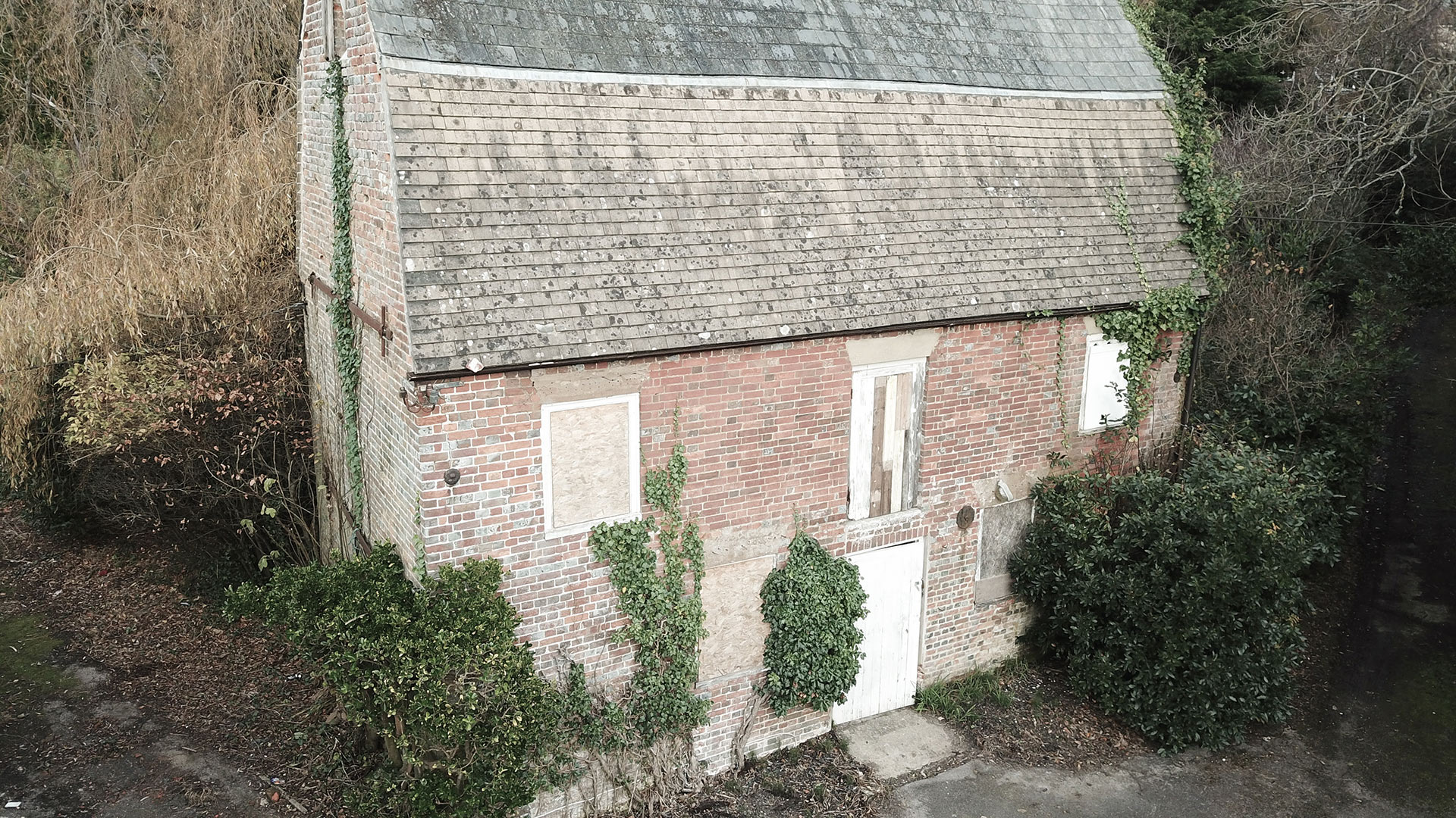 aerial side view of existing red brick house with boarded up windows