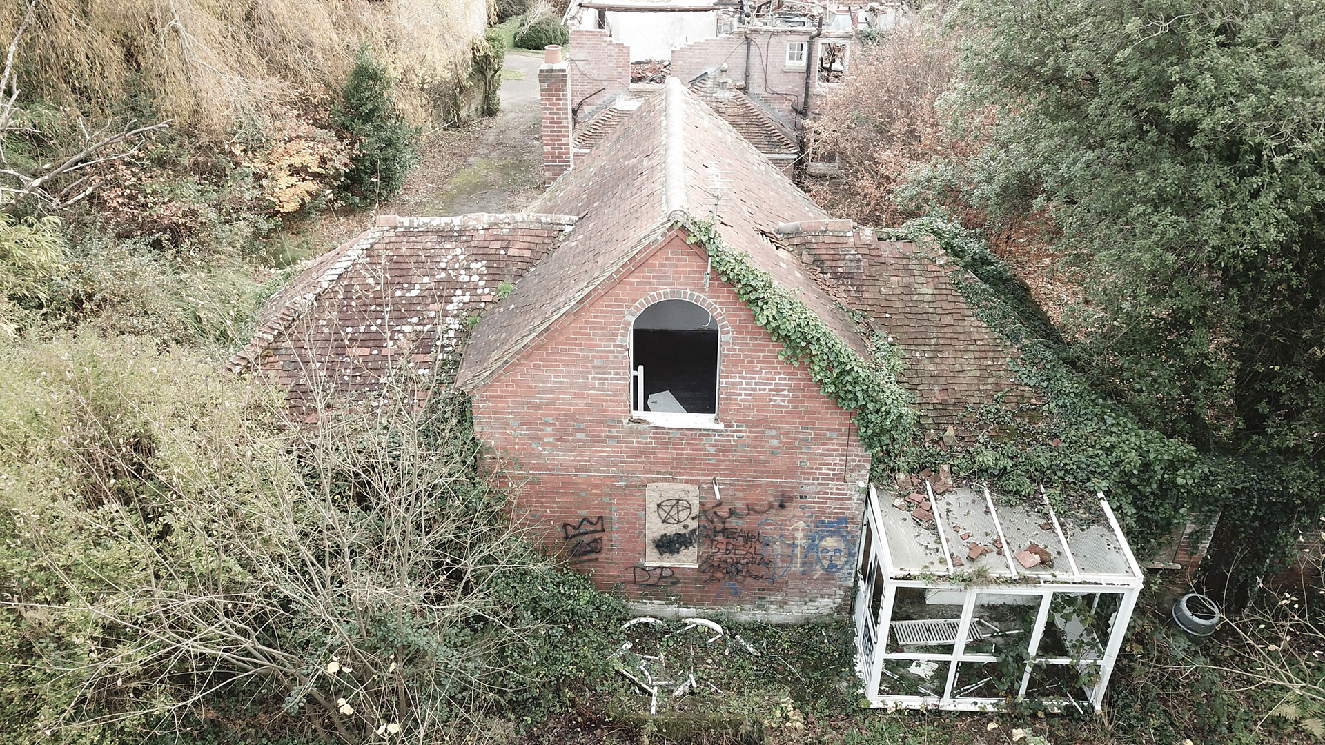 aerial view of existing red brick house with tiles falling off the roof and conservatory at rear of house
