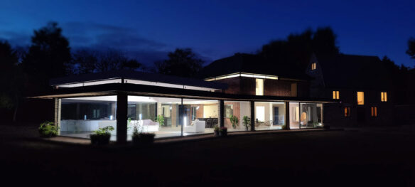 external rear view of beautiful house with large modern living area extension at night lit up