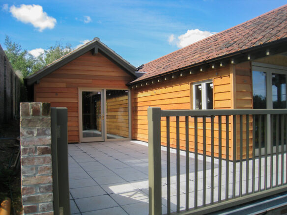 patio area outside house with wood cladding and red tiled roof
