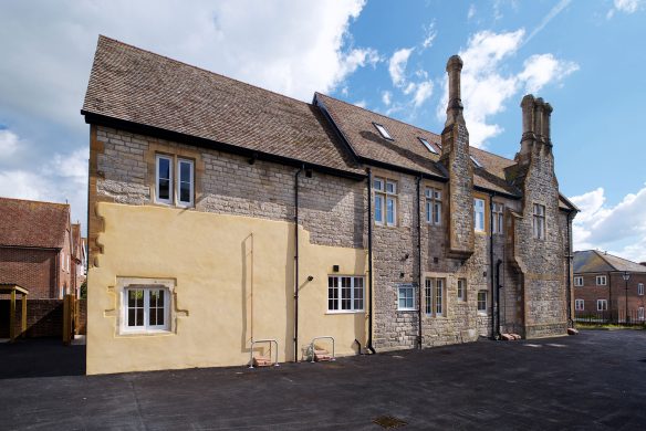 side view of converted flats with stone walls and large chimneys