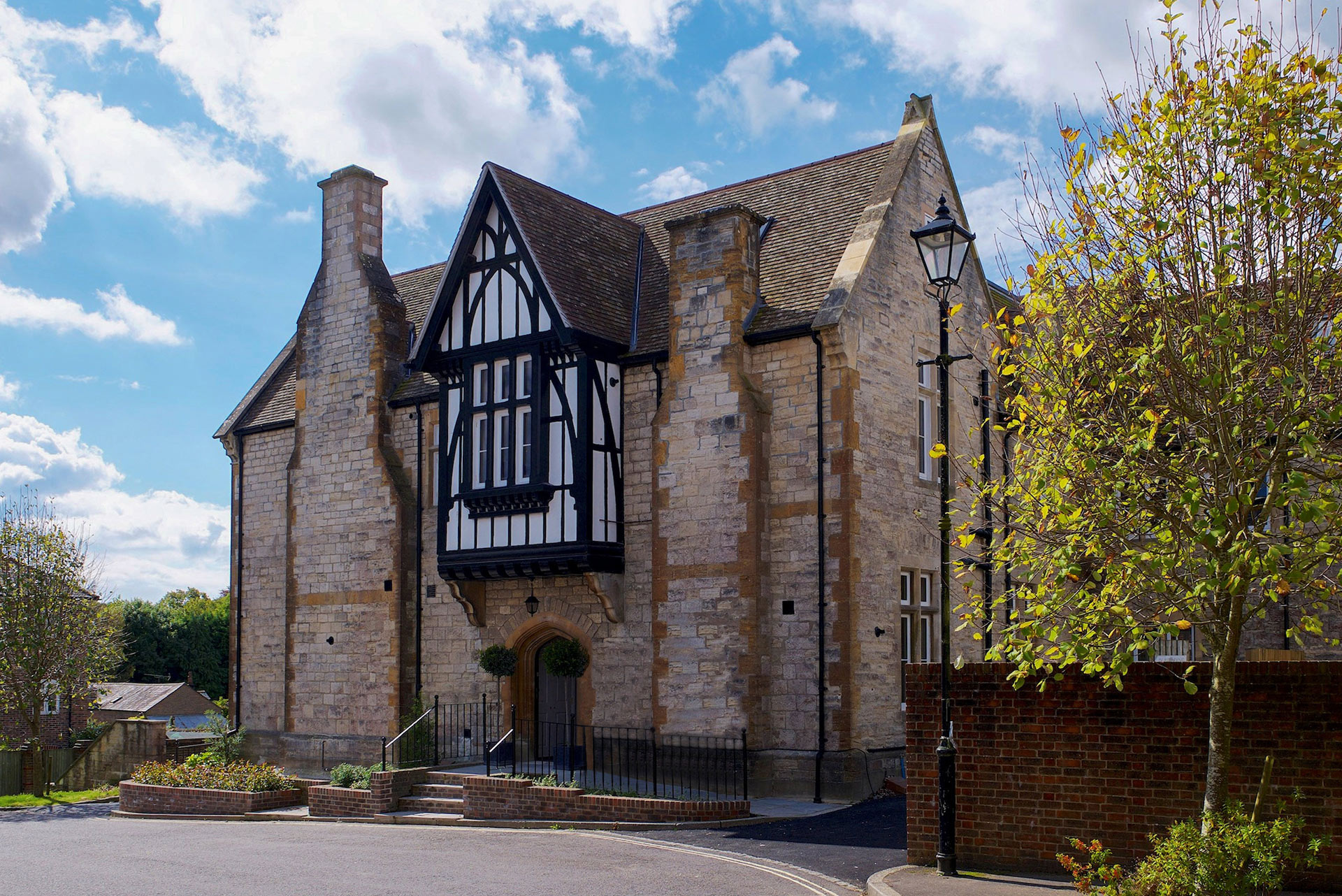 front entrance view of renovated flats with stone brickwork and oriel window taken from driveway