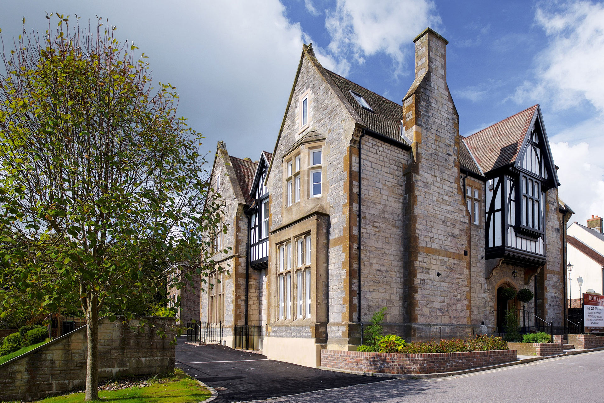 side view of large stone building converted to flats with oriel windows and chimney