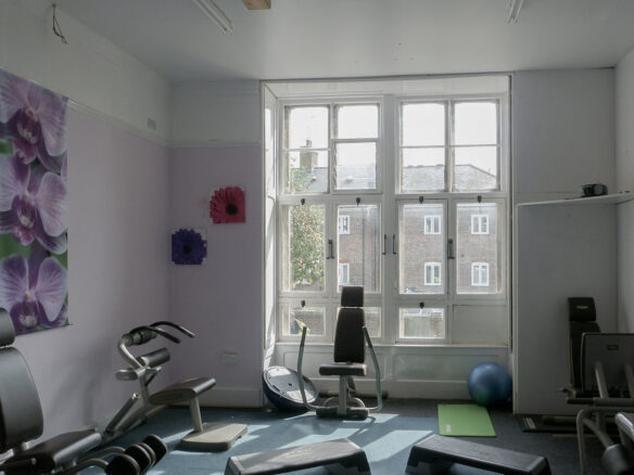 before photo of room with large ceilings and windows filled with gym equipment