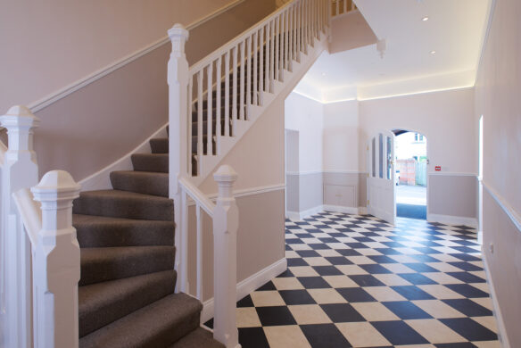 finished entrance hall with black and white checkered floor tiles and dog legged carpeted staircase