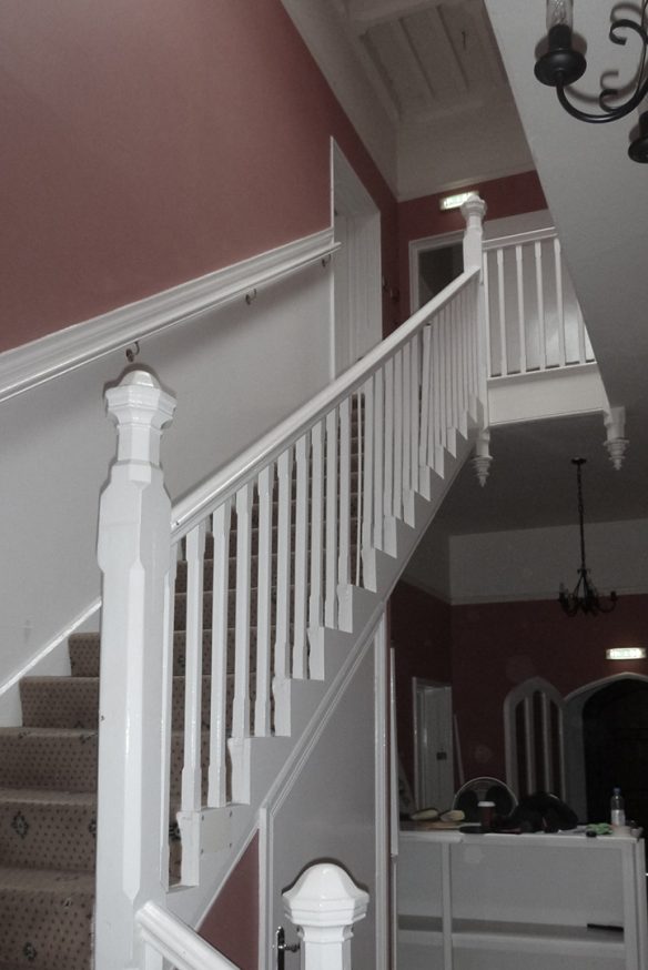 before photo of dog legged staircase with red walls and tall ceilings