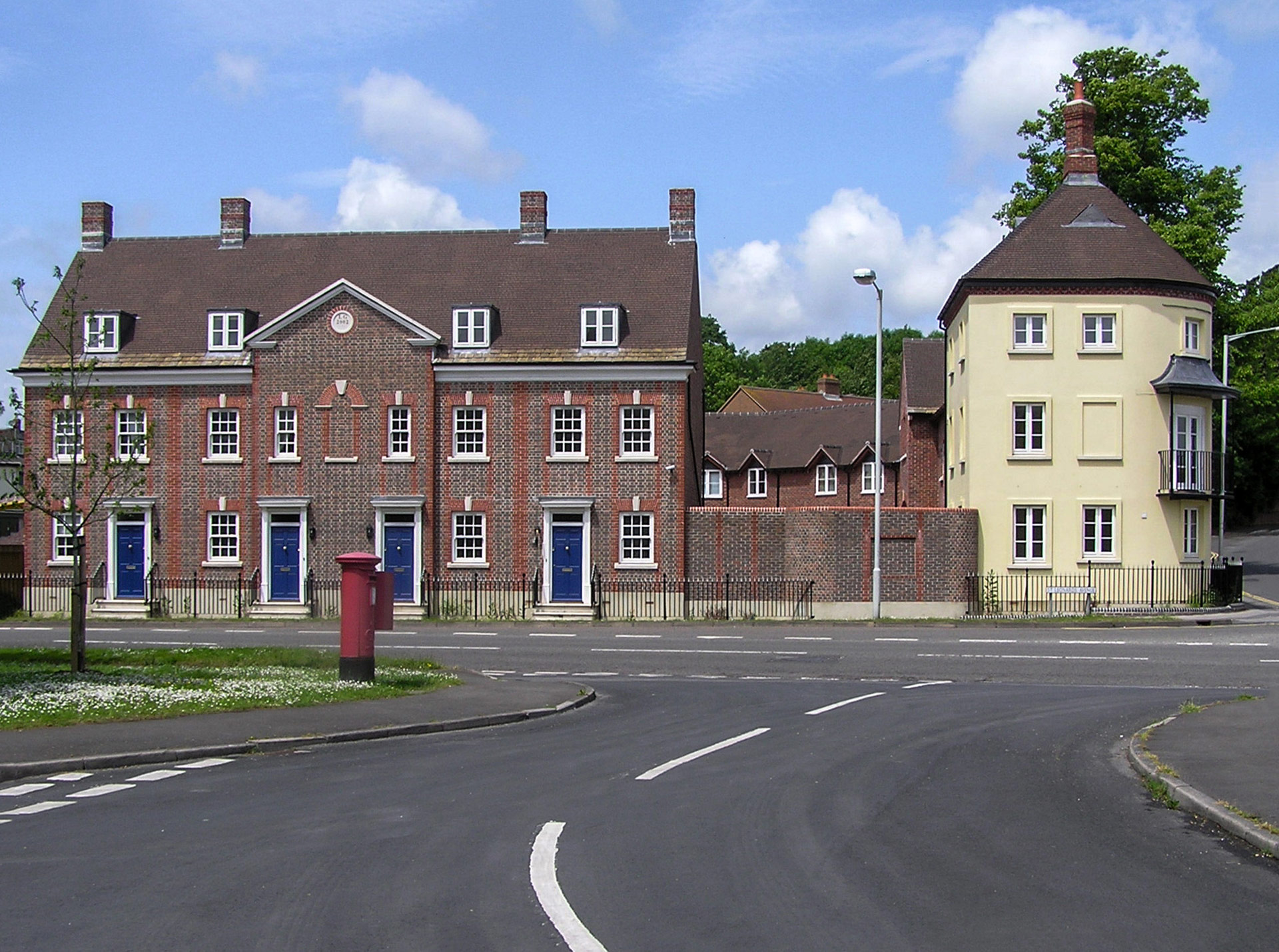 front view of terraced red brick houses and curved wall corner house from across road