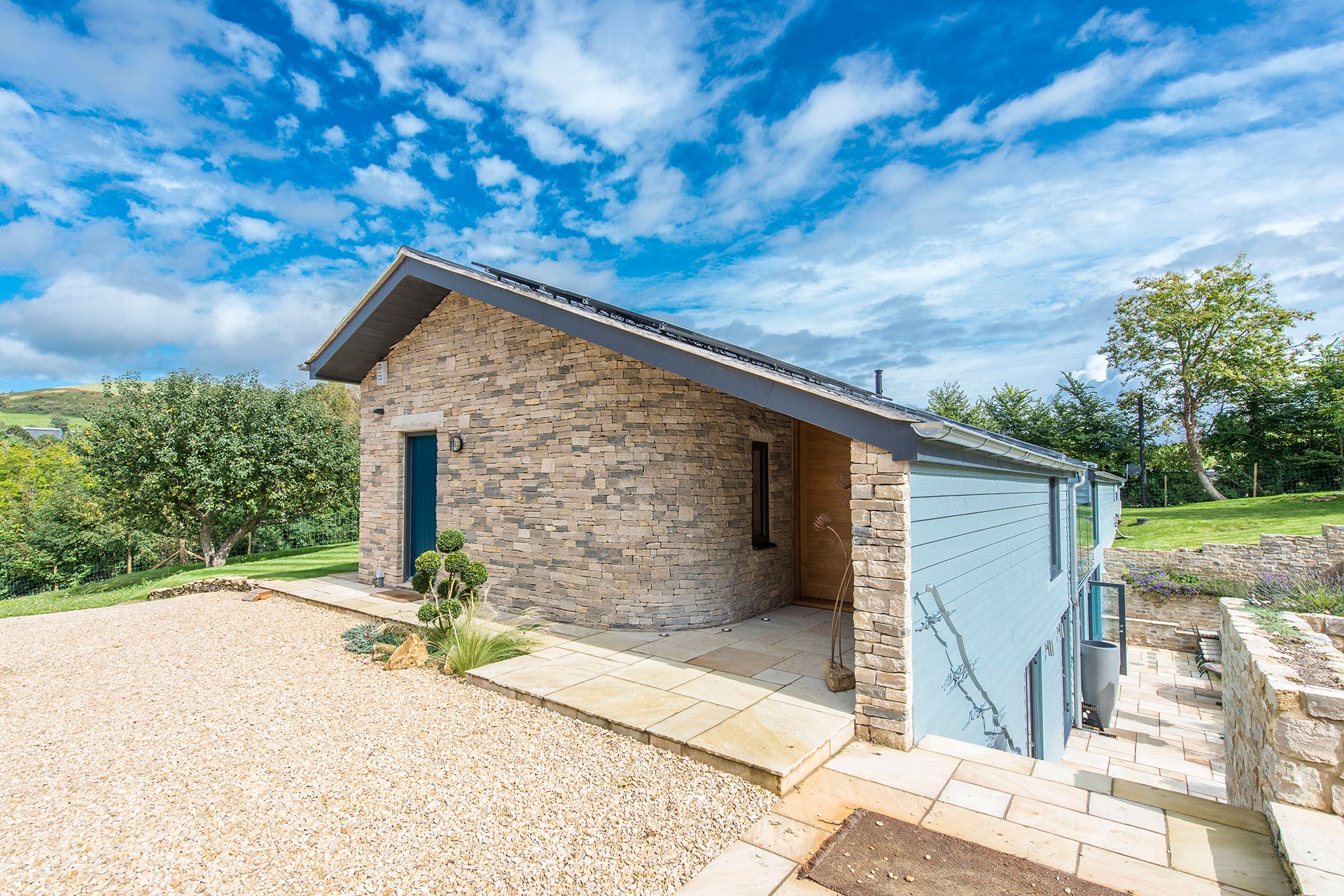 entrance view of single storey house above ground with an extensive sunken terrace and curved stone wall