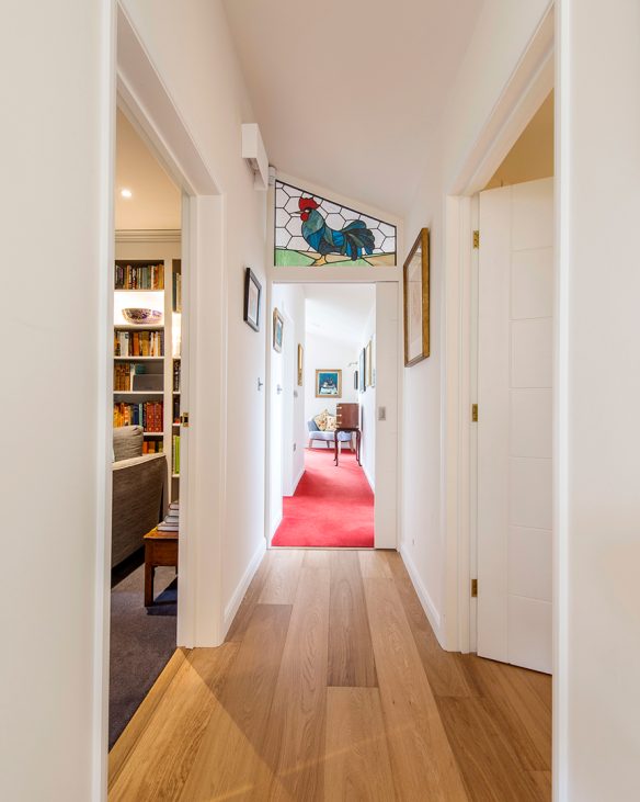 hall way with slanting roof and stained glass window of cockerel