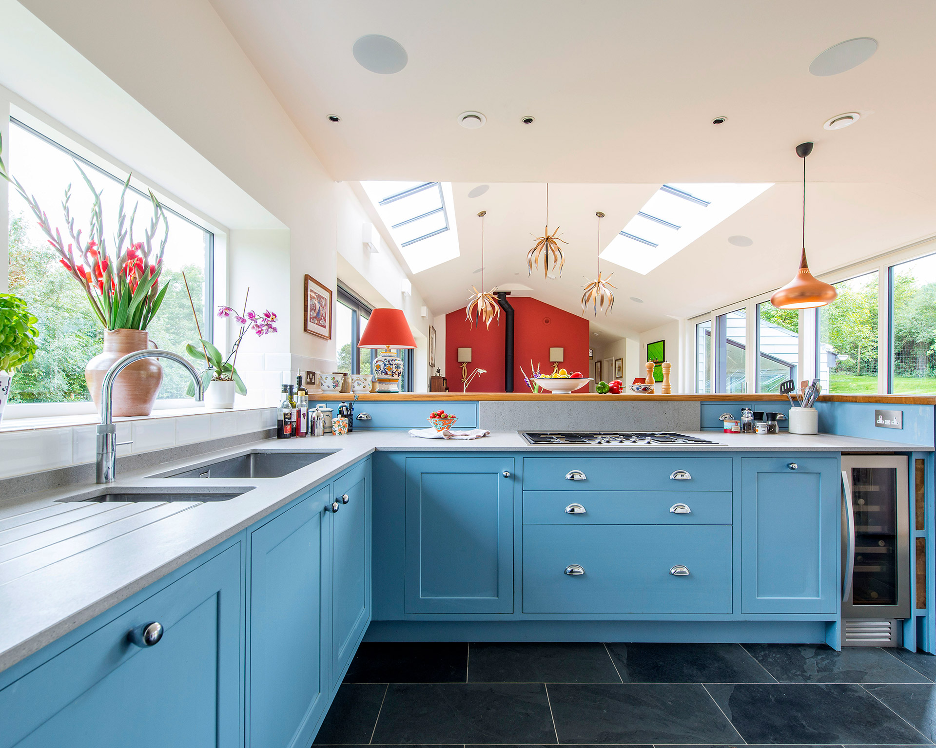 open plan kitchen living room area with blue cabinet doors and unique light fittings