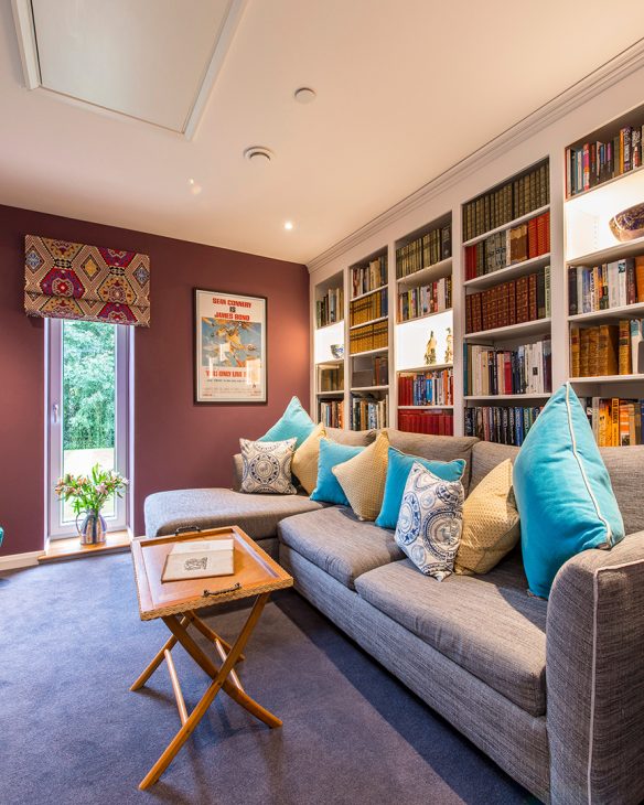 beautifully decorated snug living room with book shelf feature wall and large corner grey sofa