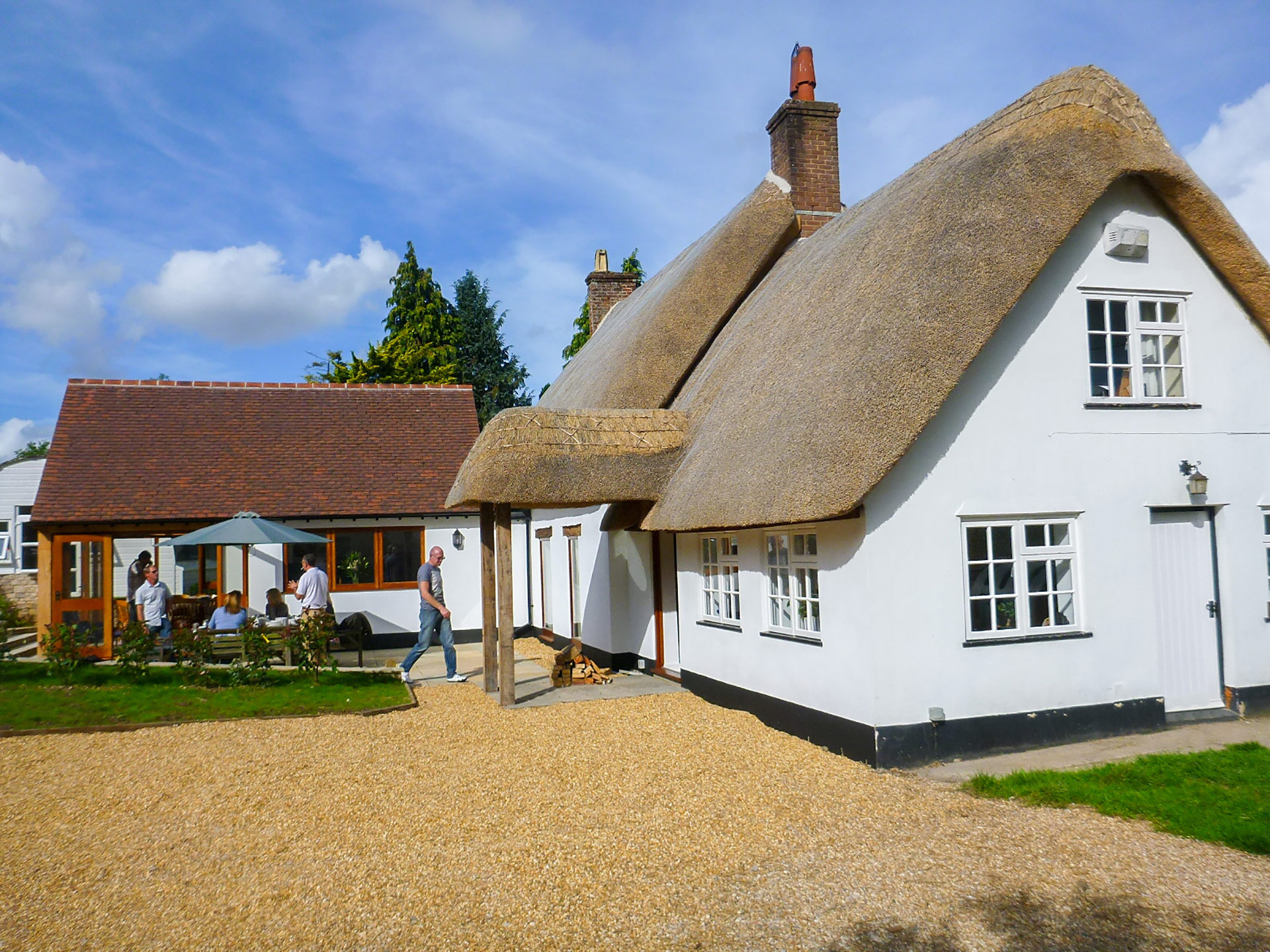side view of thatched cottage with red tiled roof extension