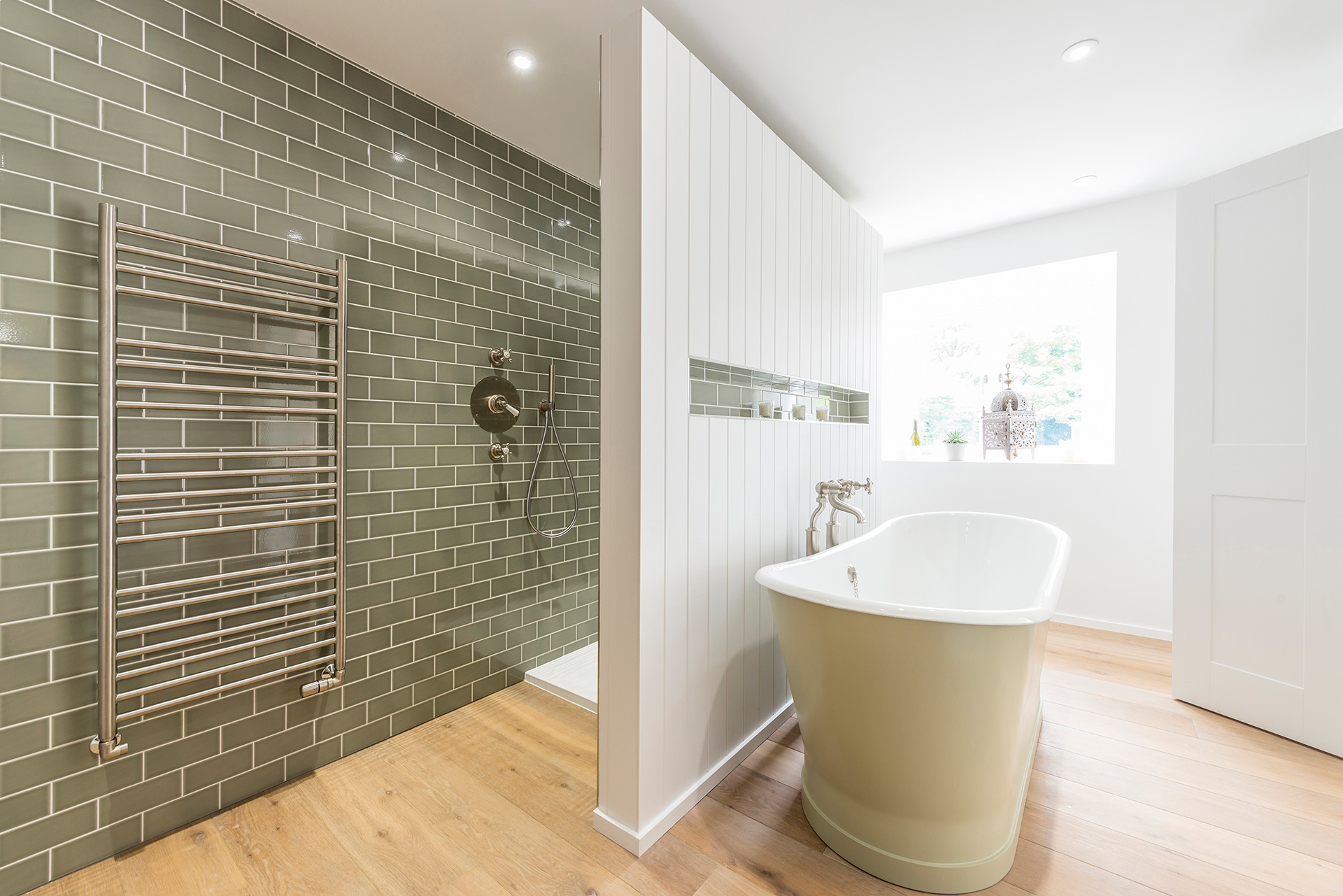 modern large bathroom with large freestanding bath and green wall tiles in shower