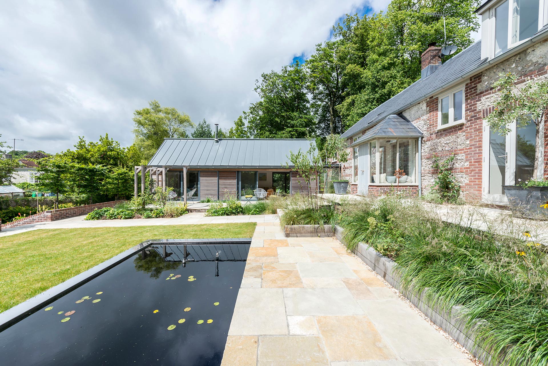 garden view of extension to traditional cottage with pond and patio area