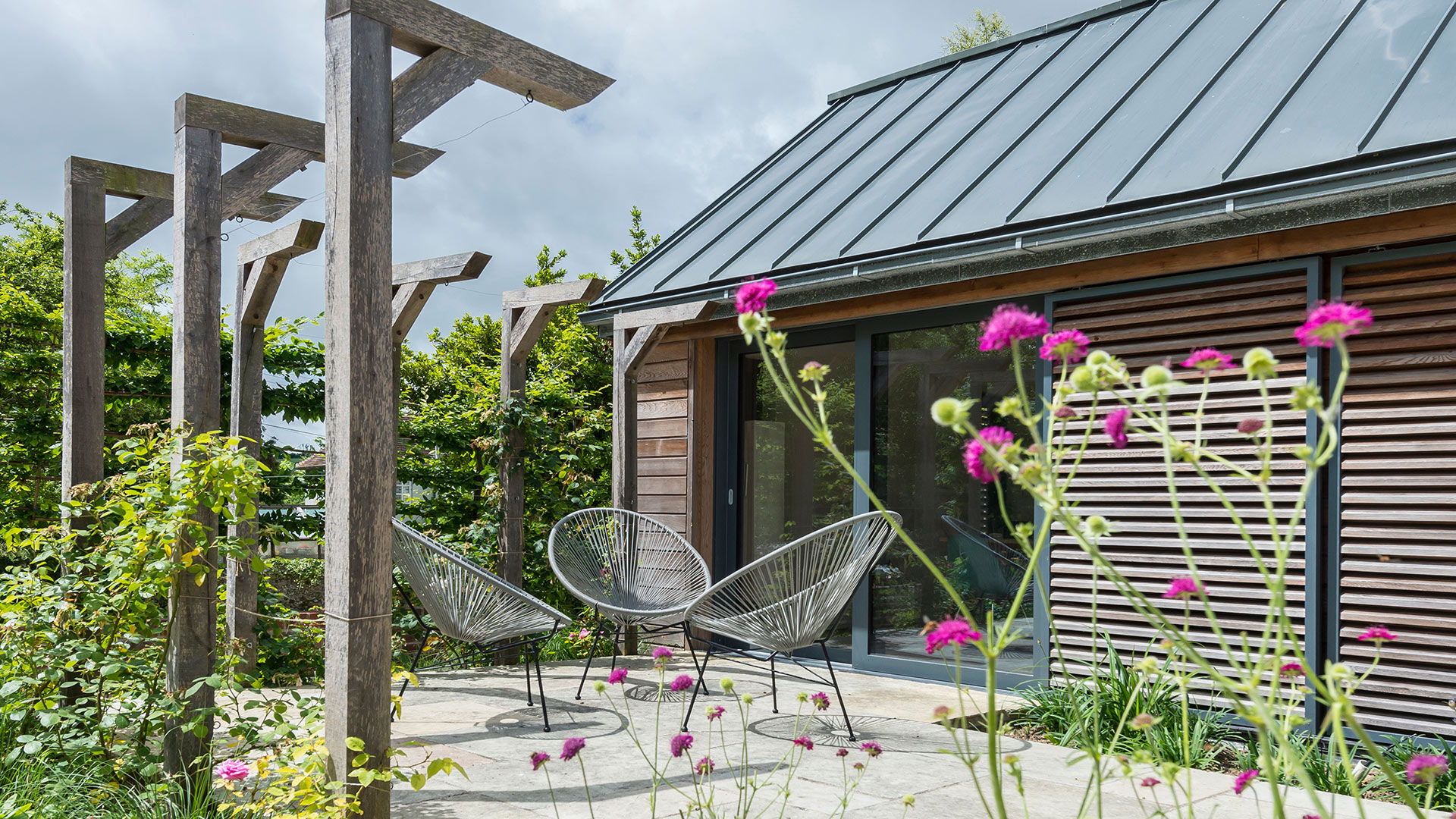 detailed photo side view of extension with timber cladding and sliding doors leading to patio area