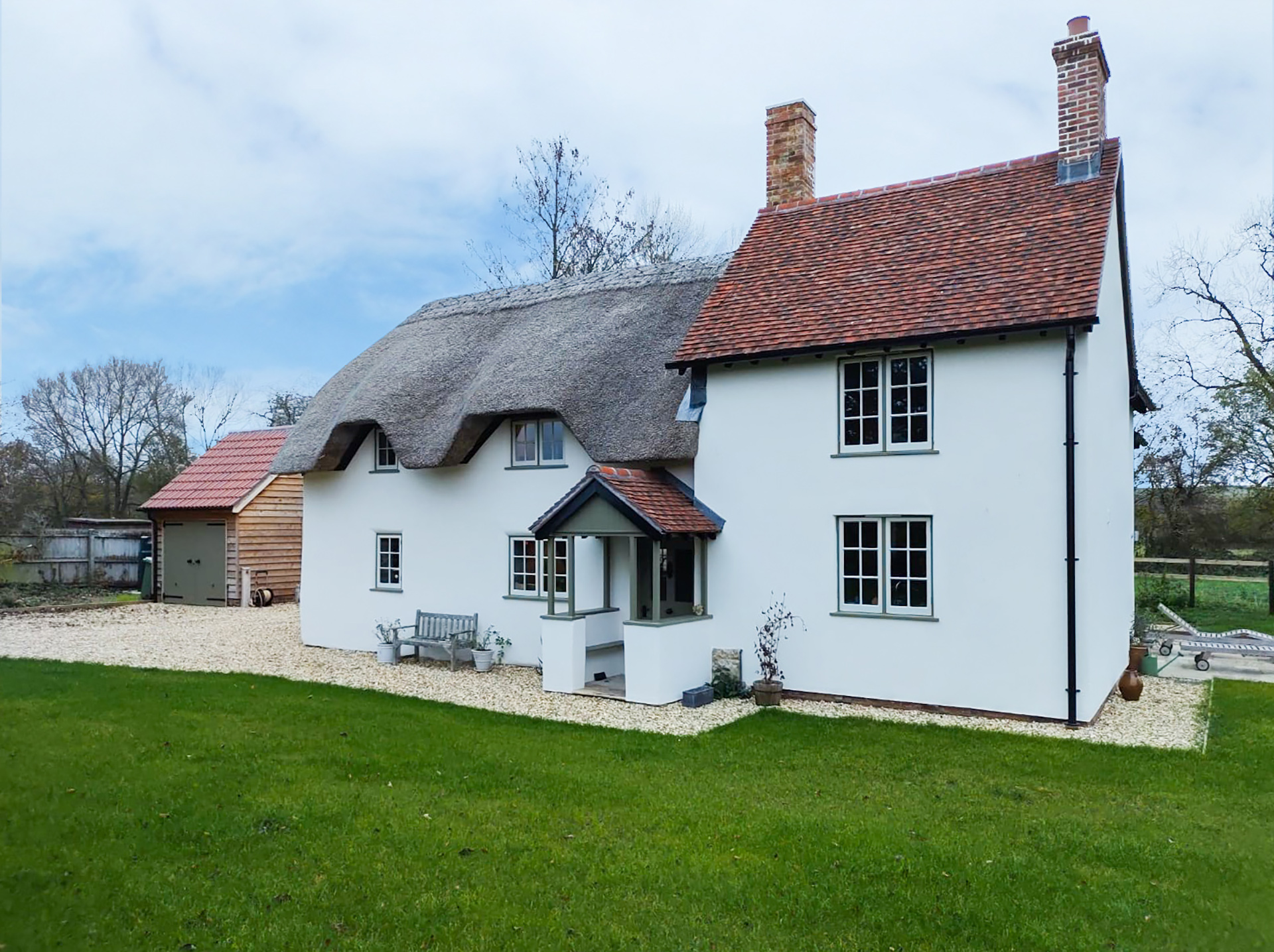 Front view of finished white house with red tiled and thatched roof