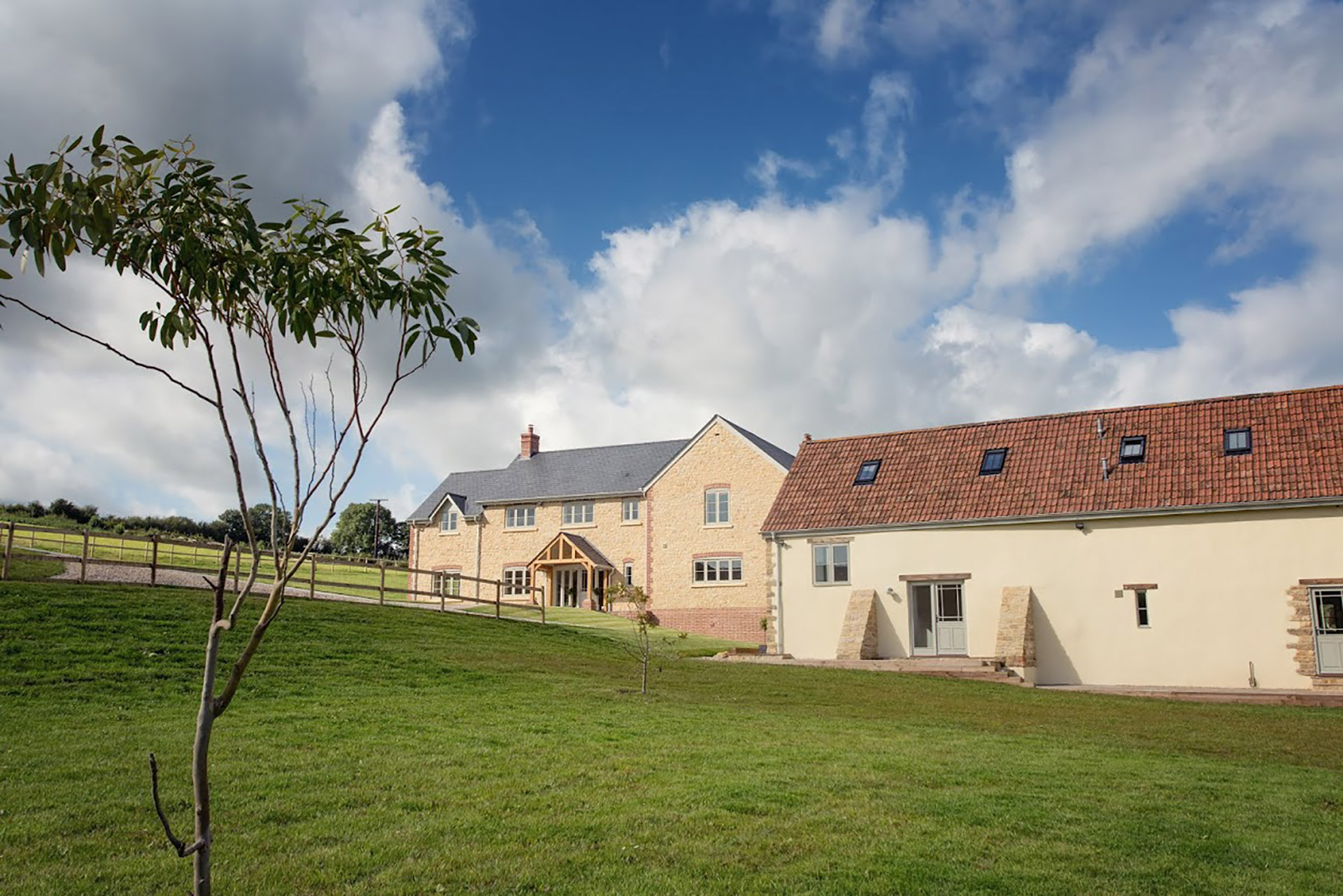 front view of finished large stone farmhouse and annex with red tiled roof