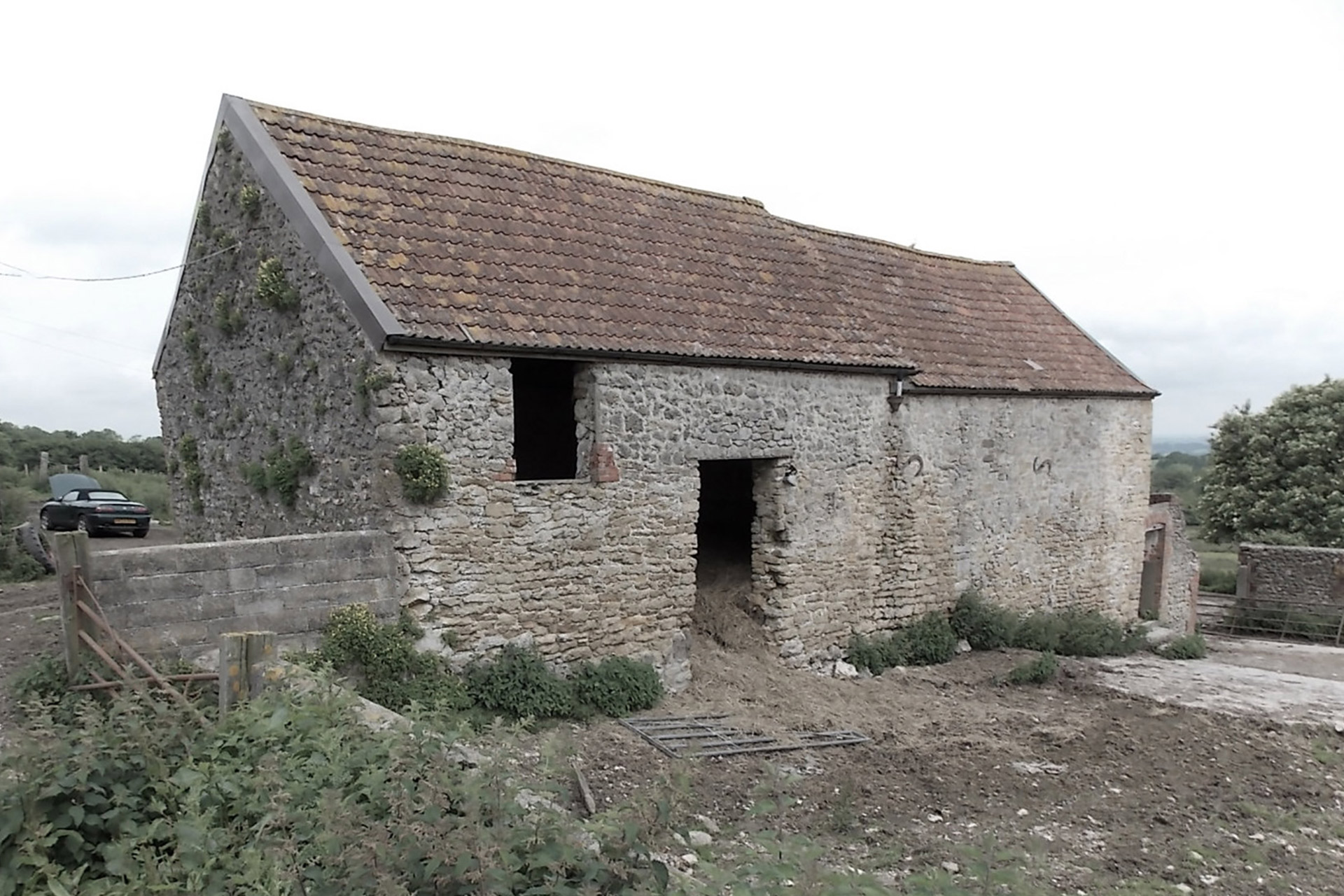 before photo of stone barn with tiled roof