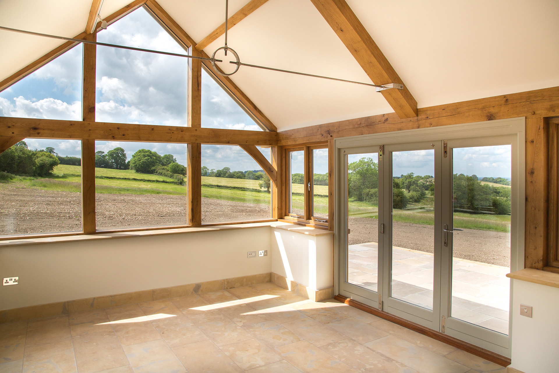 interior photo of sunroom with exposed wooden beams and beautiful countryside views