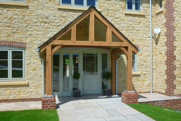 main entrance to farm house with exposed beams around porch and stone walls