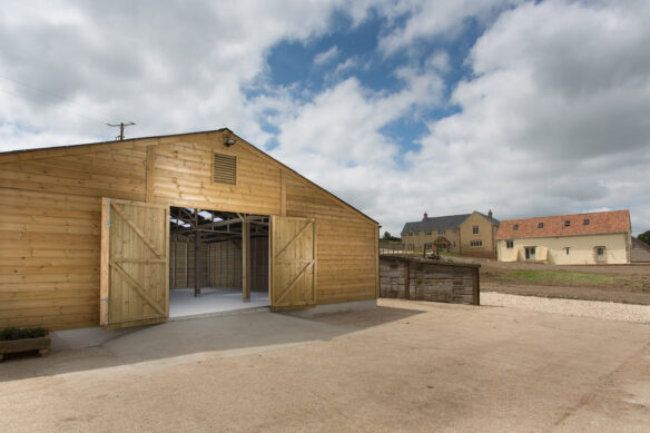 new barn stables with timber cladding, new farmhouse and annex in distance behind