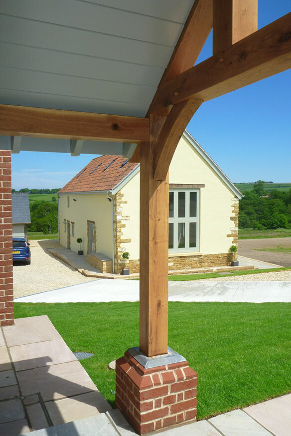 external view from entrance of farmhouse with timber pillar on porch towards annex