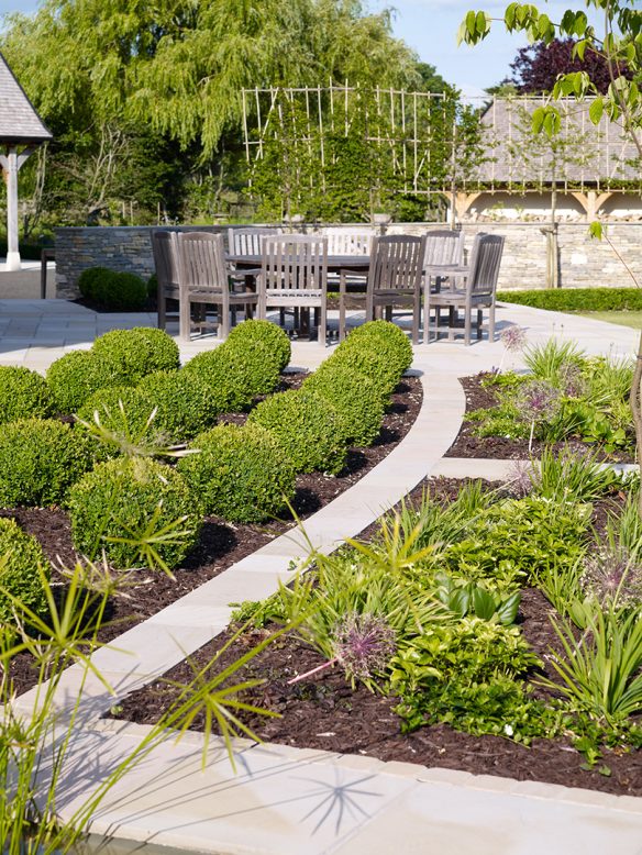 landscaped garden with shrubbery and table and chairs in distance