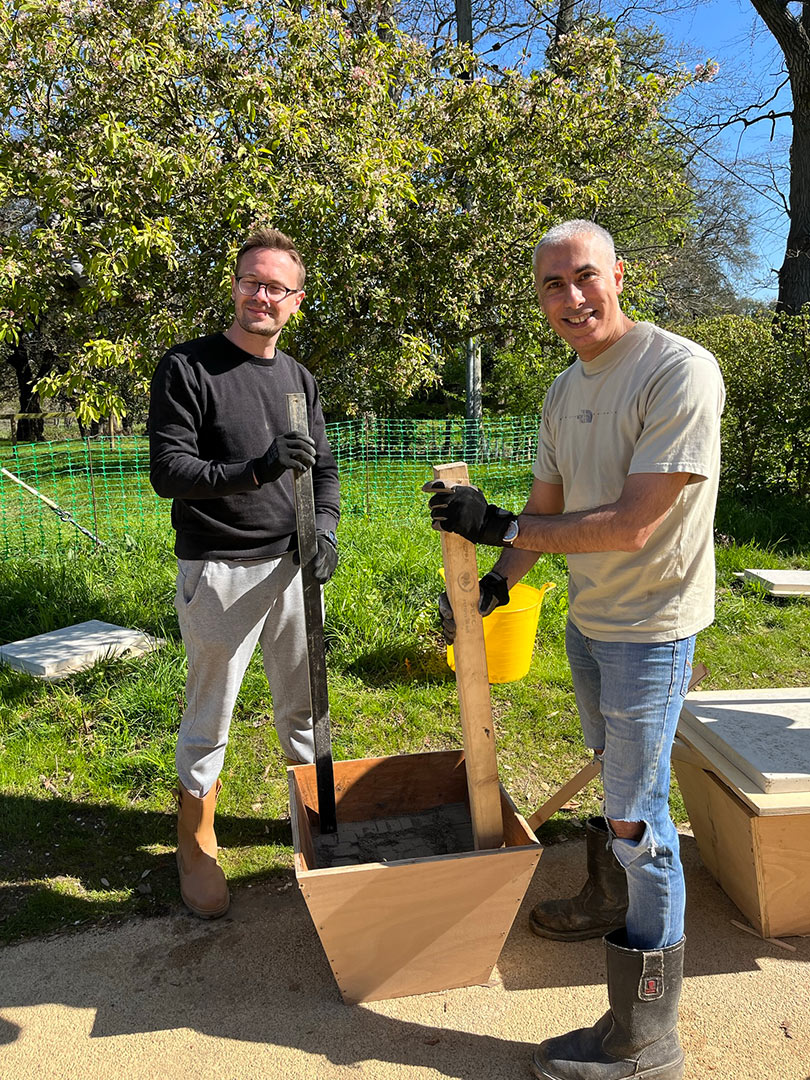 two men smiling compacting soil in bucket