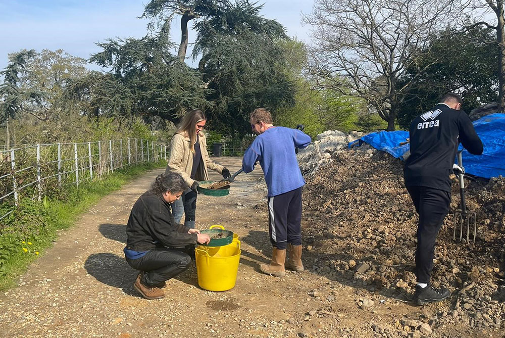 group of people filtering soil into buckets