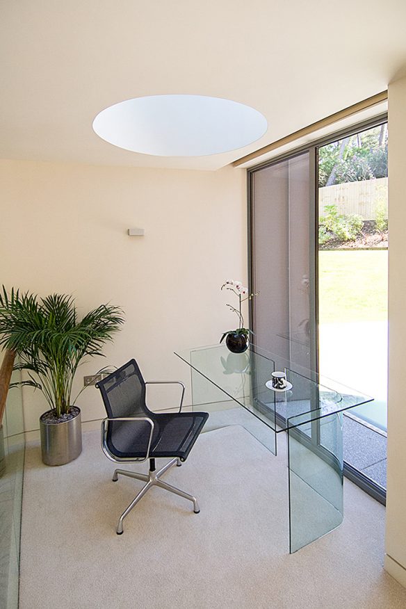 office room with glass desk and light well in ceiling