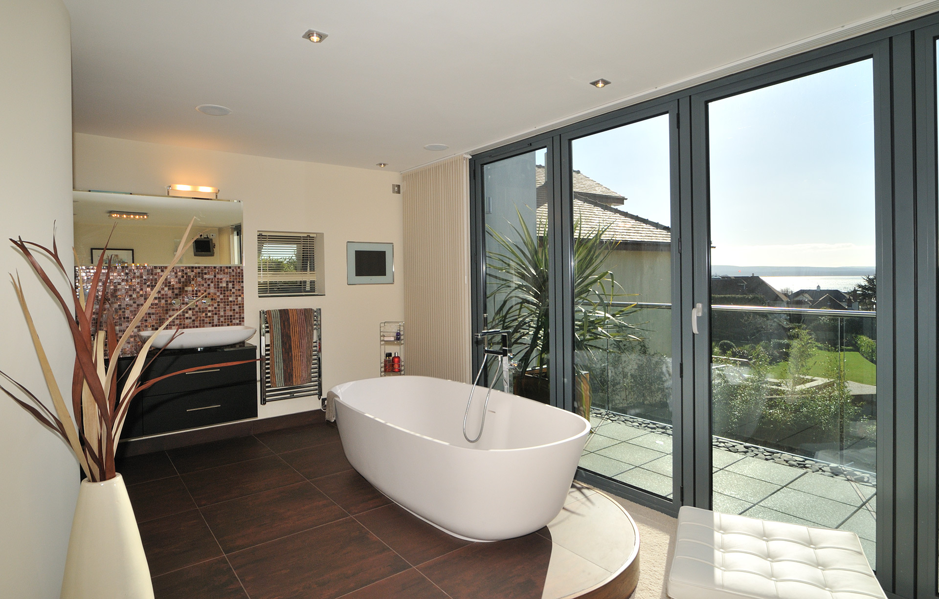 free standing bath with glass double doors leading to balcony with sea views