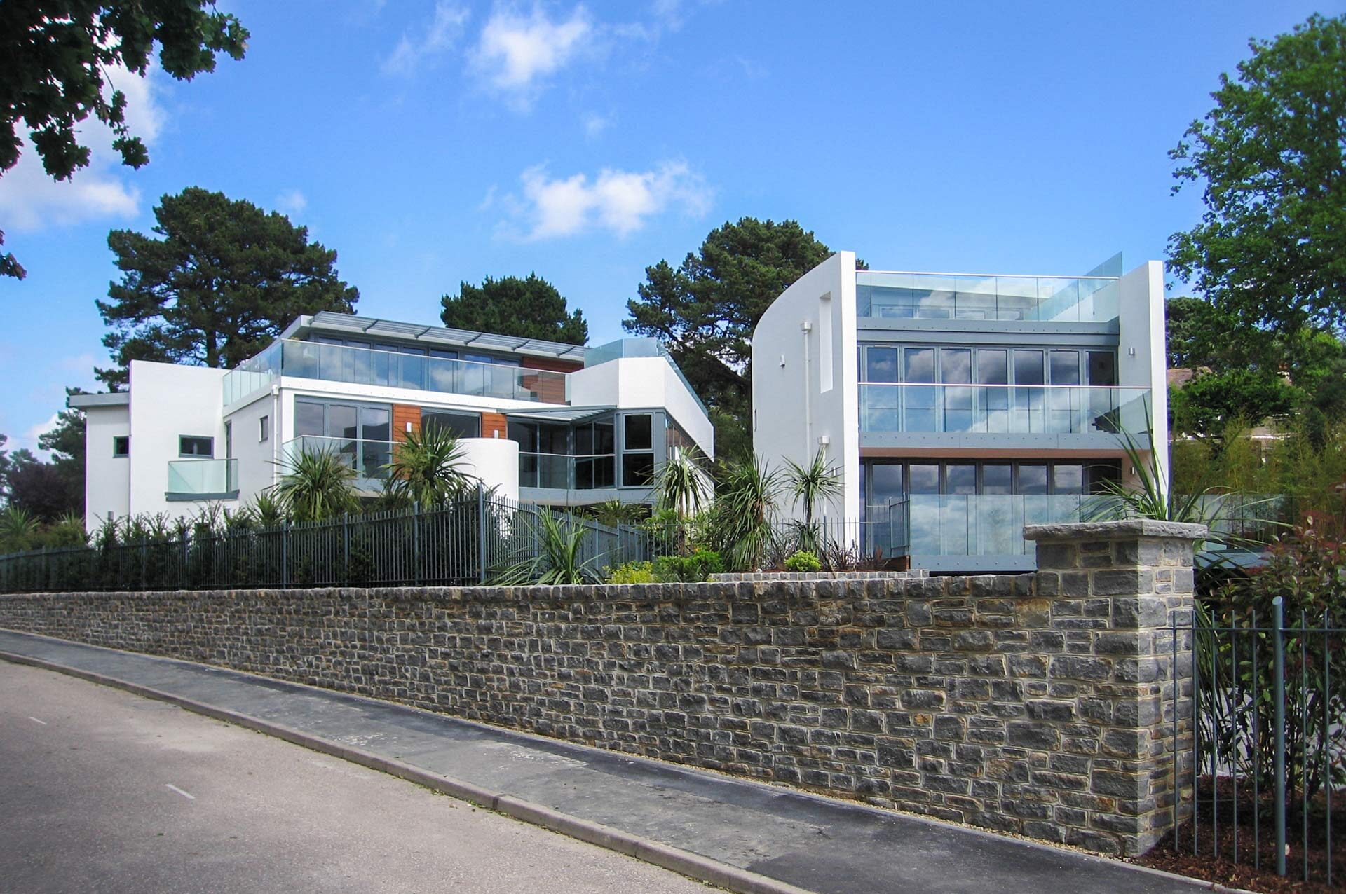 street view of two modern white houses with curved wall and balconies with glass balustrade