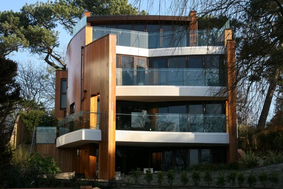 front view of house with curved walls and balconies with glass balustrade