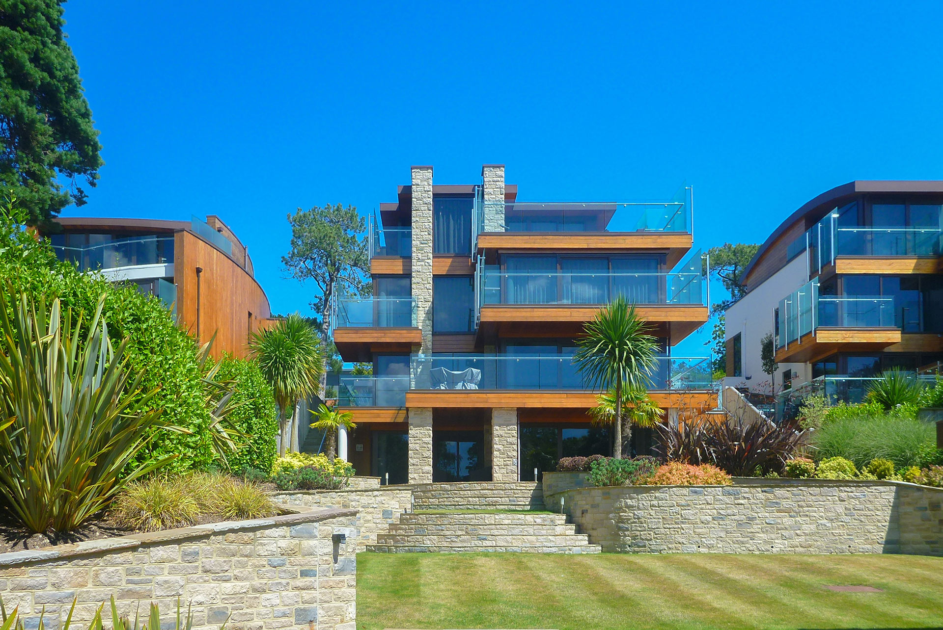 garden view of house with modern linear design and glass balconies with glass balustrade