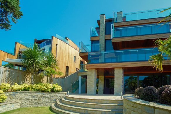 garden view of house up close with modern linear design and balconies with glass balustrade