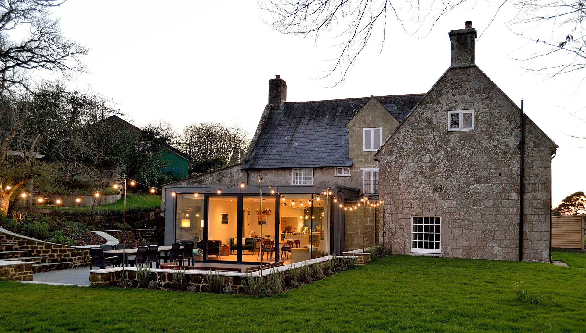 contemporary extension on traditional stone house at dusk