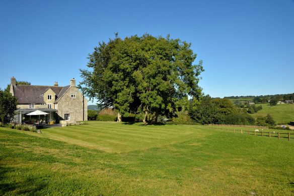 rear view of stone house with modern extension with large grass lawn