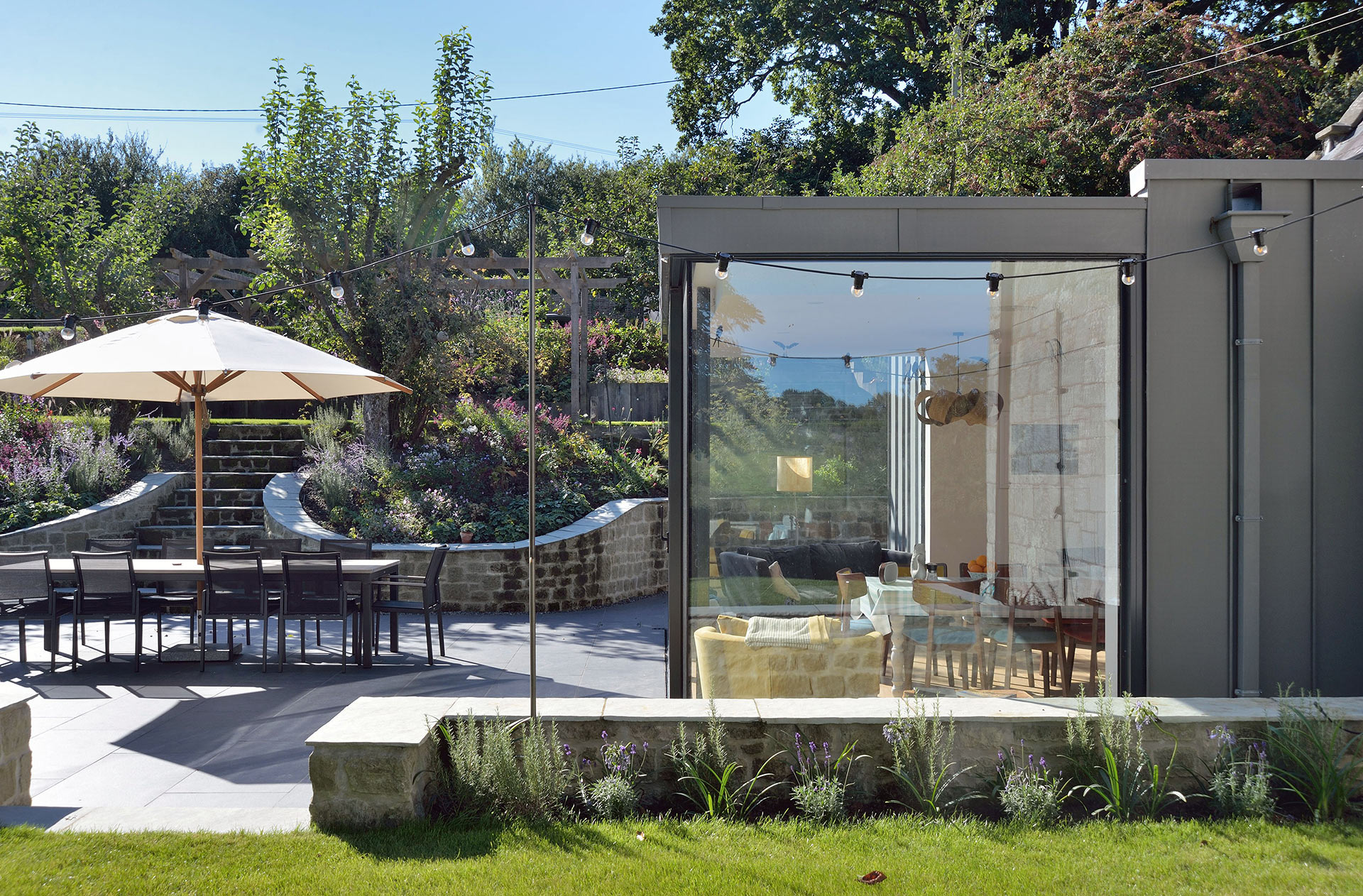 side view of modern extension with large glass panels leading onto garden terrace