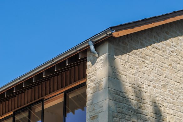 roof detailing on house with reclaimed oak for lintels, galvanised steel guttering and downpipes, and batten and board vertical timber cladding