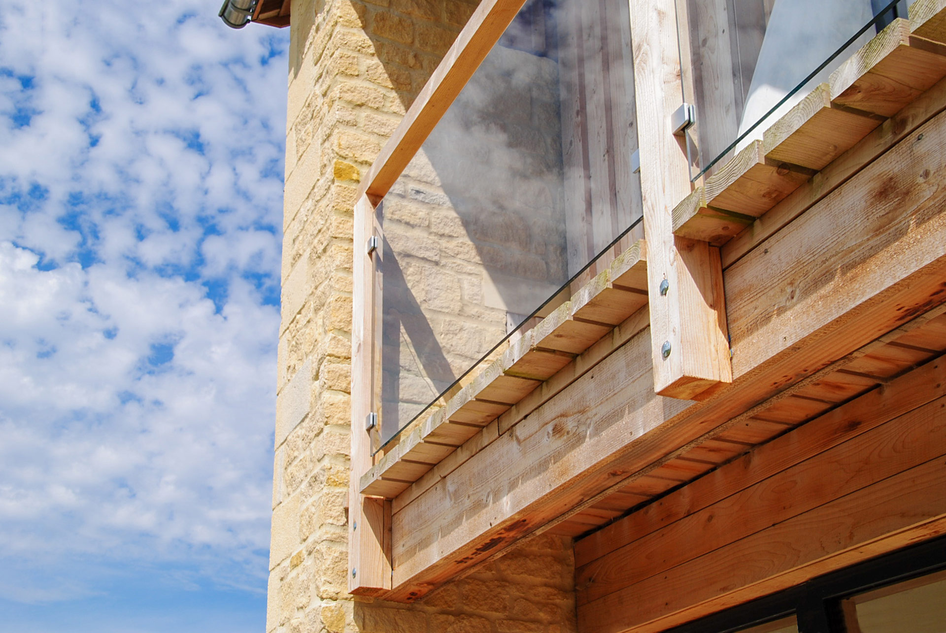 detail photo of balcony with glass balustrade attached to stone house