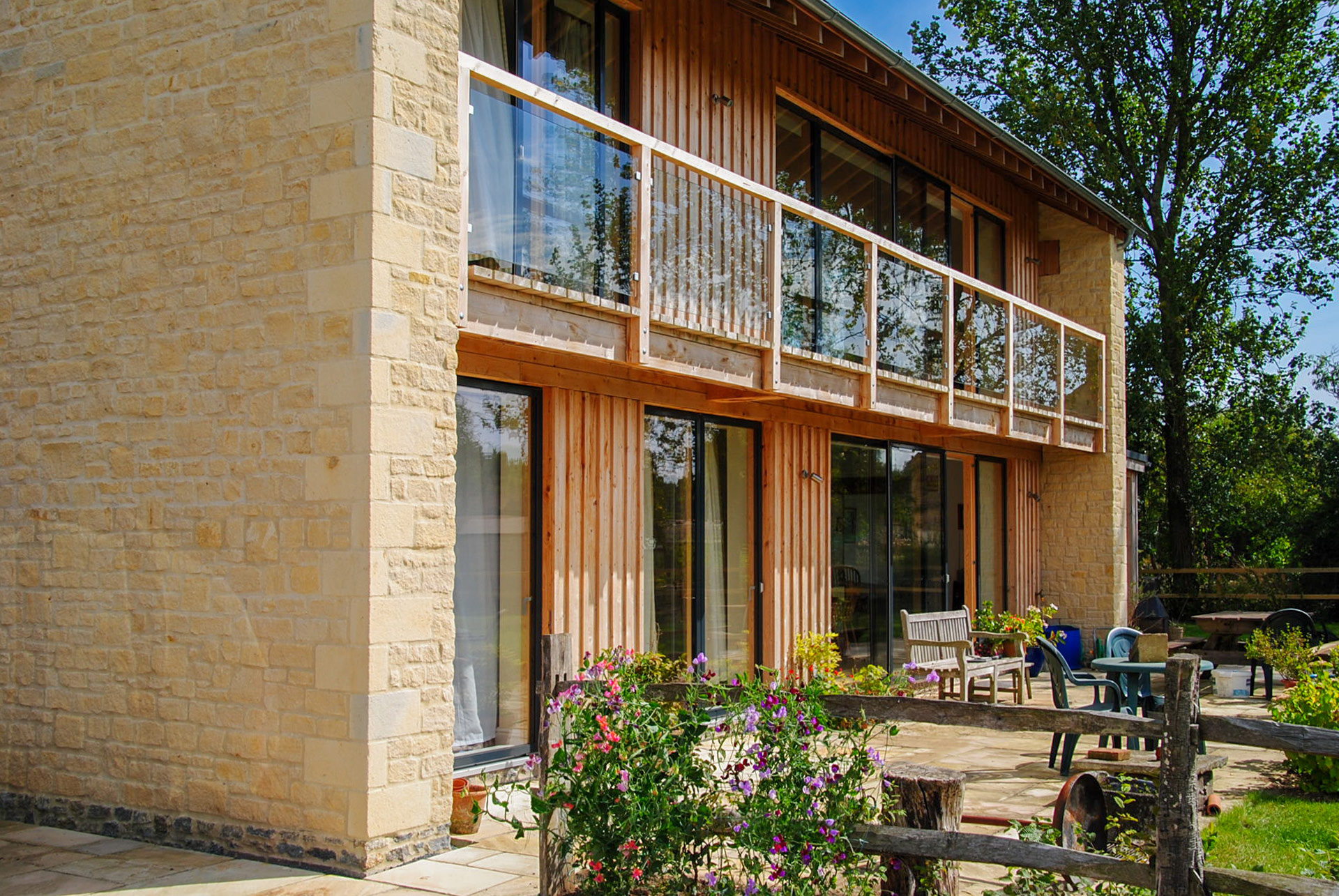 timber and stone house with balcony and view of outside patio area