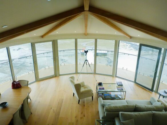 aerial photo of living space with curved vaulted ceiling with exposed beams and beautiful river views