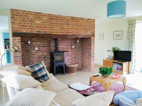 living space with log burner red brick fireplace