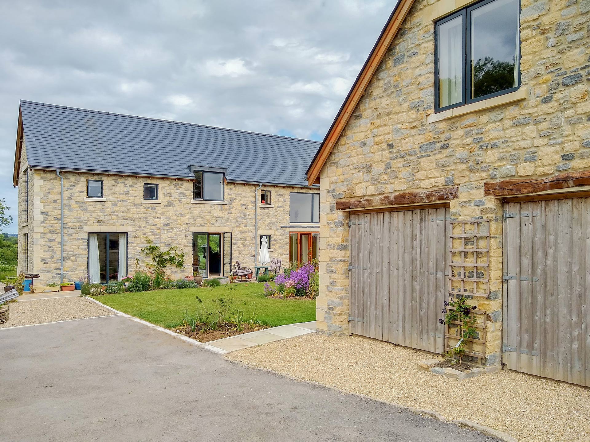 stone garage with double door and large stone house behind