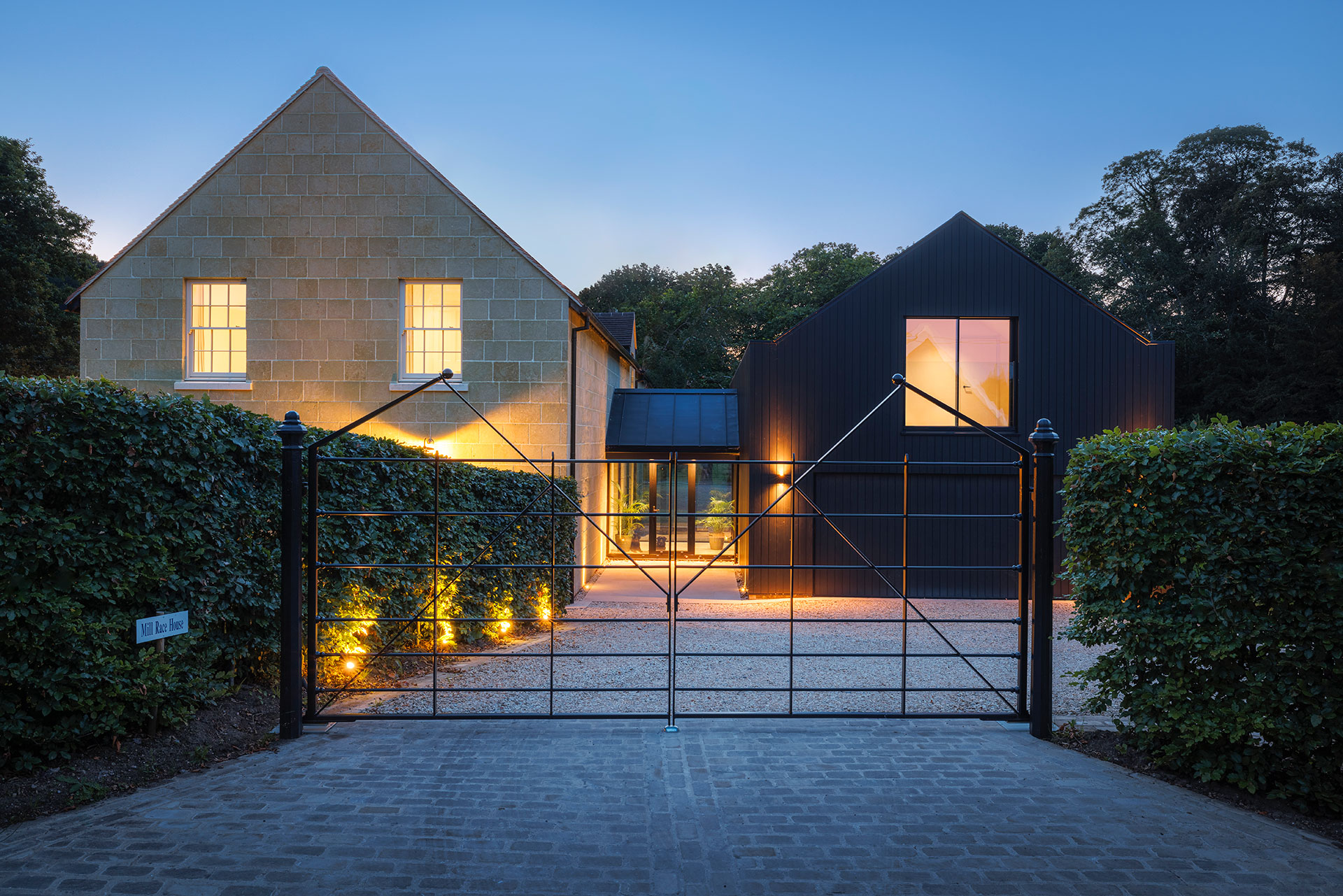 entrance to house behind black gate at dusk with lights on