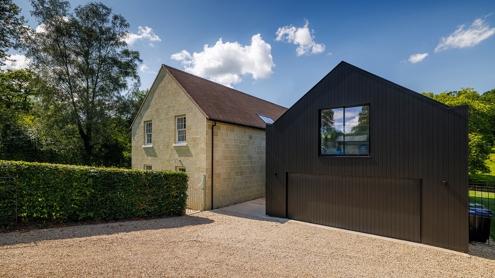 entrance approach to house with large black barn and pebble drive