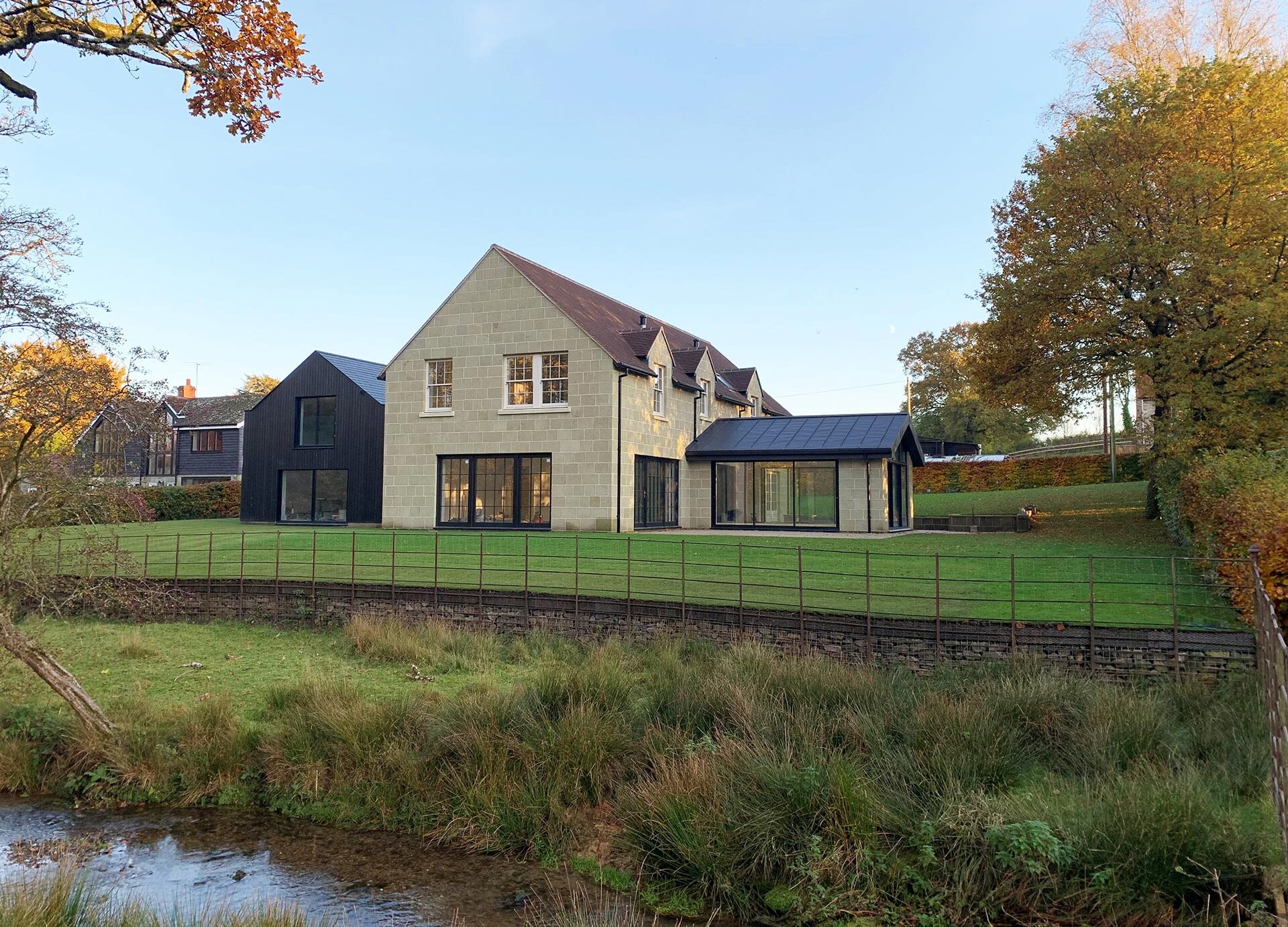 side elevation of stone house with extension taken from across river